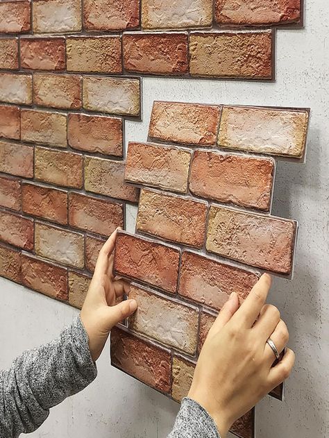 two hands are placing bricks on the wall to make it look like they have been built into