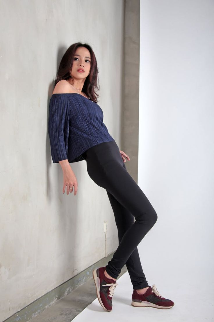 a woman leaning against a wall wearing leggings