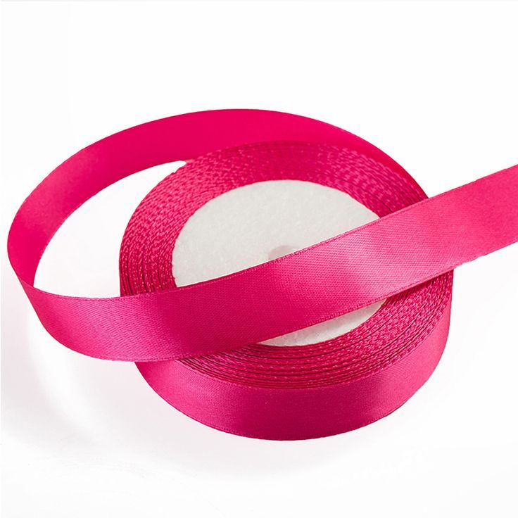 a roll of pink satin ribbon sitting on top of a white surface with one piece cut off