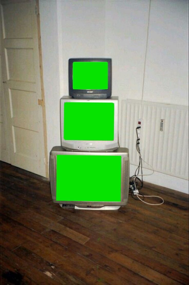 two televisions stacked on top of each other in a room with wooden floors and white walls