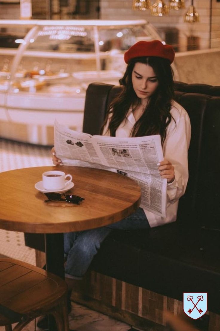 a woman sitting at a table reading a newspaper