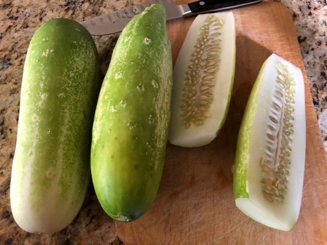 three cucumbers on a cutting board with a knife