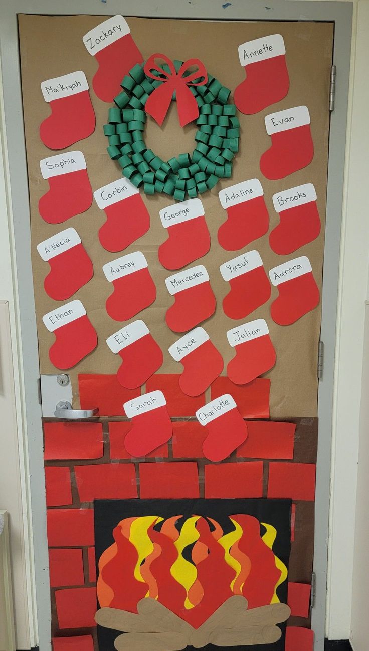 a bulletin board is decorated with red and green paper hearts, a wreath, and a fire place