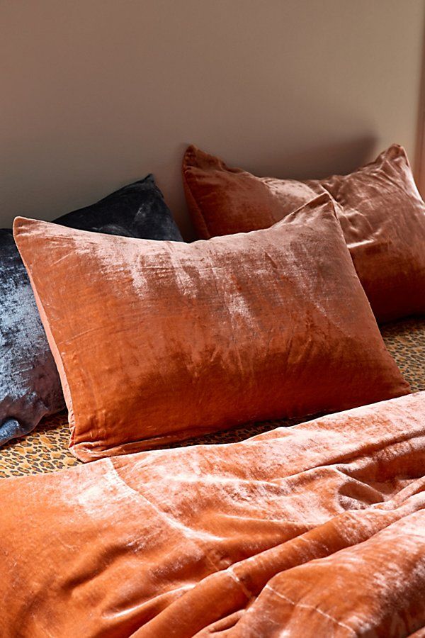 a bed with orange and black pillows on it