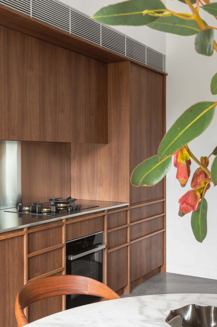 a modern kitchen with wooden cabinets and stainless steel appliances, along with a marble dining table