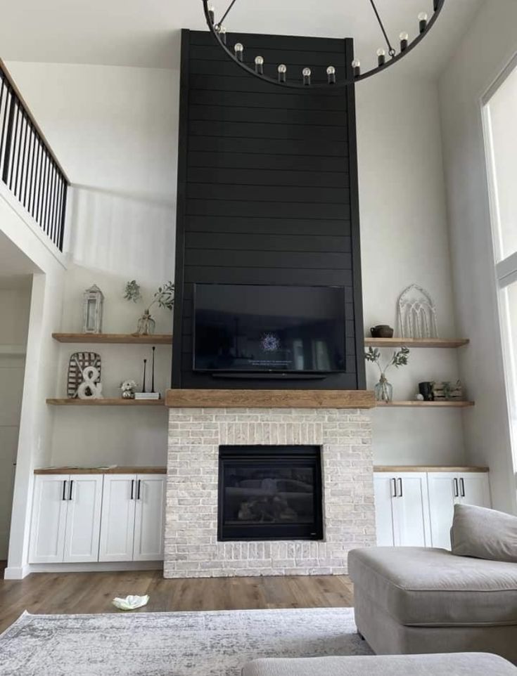 a living room with white furniture and a large tv mounted on the wall above a fireplace