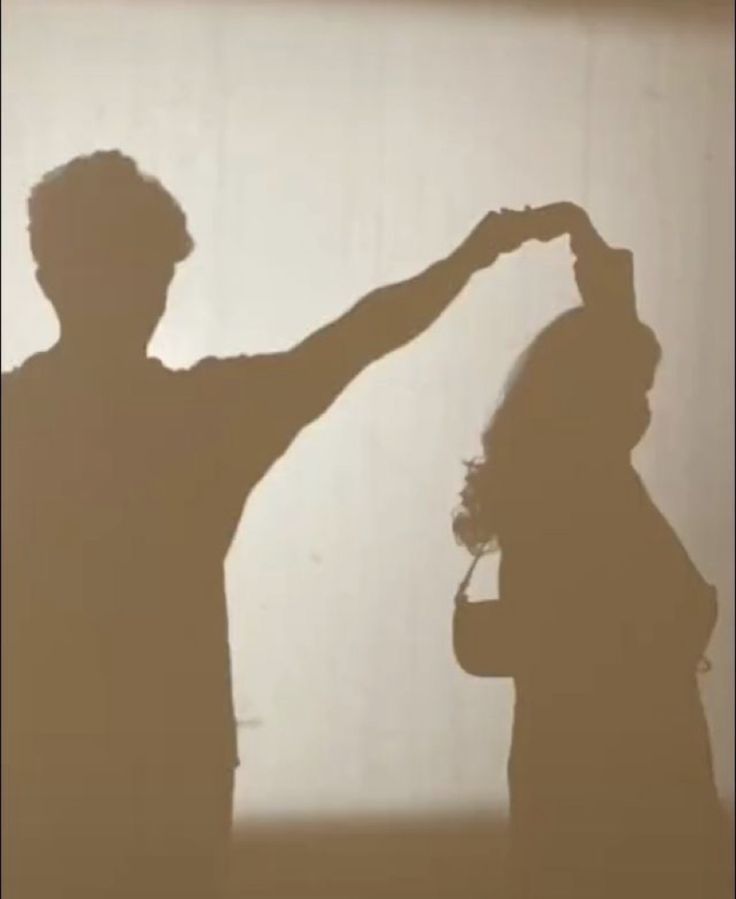 two people standing in front of a wall with the shadow of one person's head