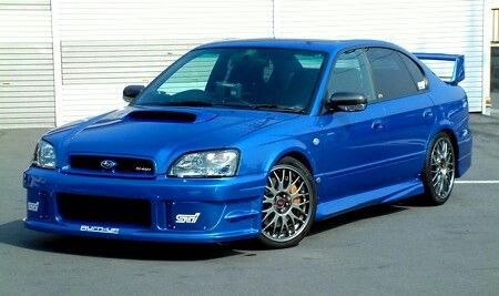 a blue subarunt is parked in a parking lot next to a garage door