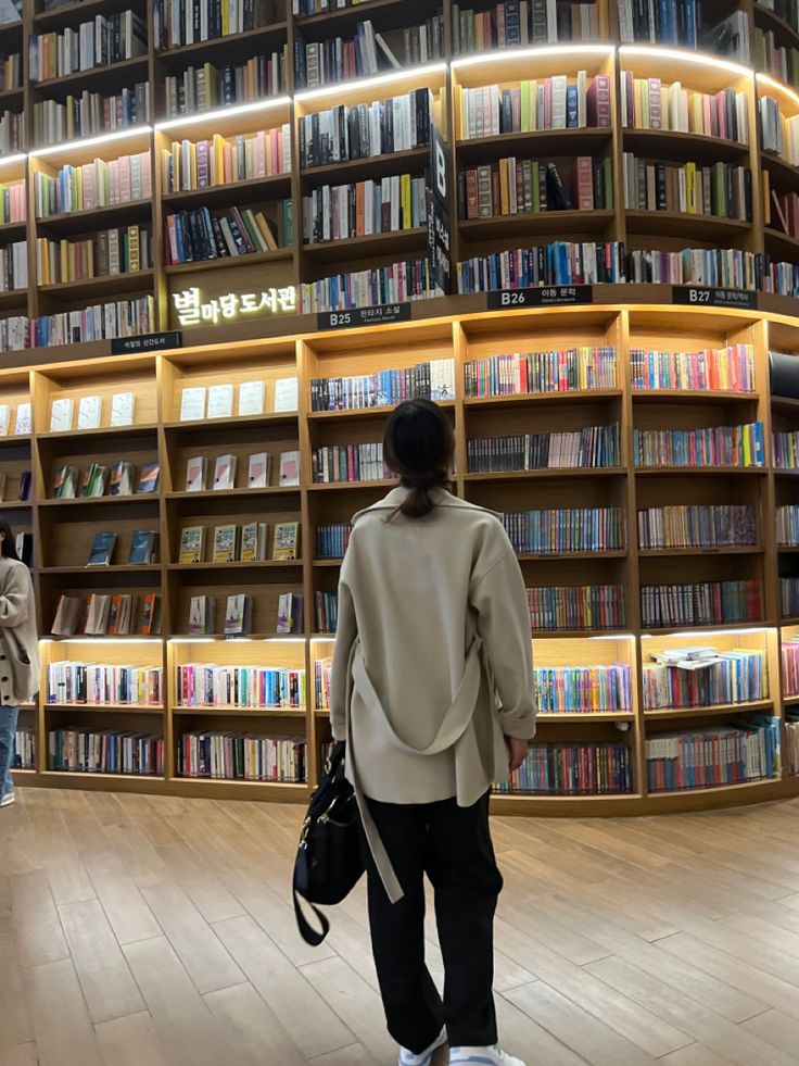 a person walking in front of a book shelf filled with books