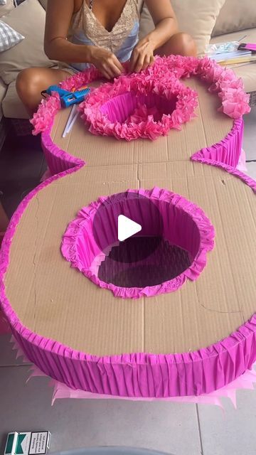 a woman sitting on a couch cutting paper with scissors and pink flowers in front of her