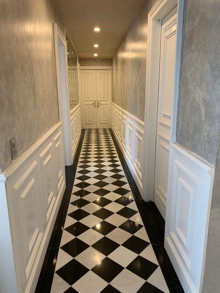 an empty hallway with black and white checkered flooring on both sides, leading to another room