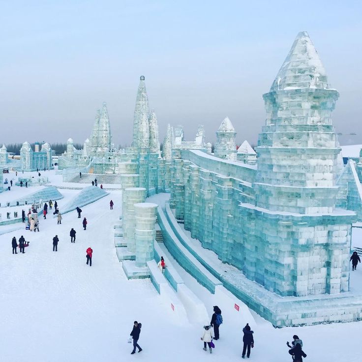 many people are walking around in the snow near ice sculptures and water fountains that look like they have been frozen