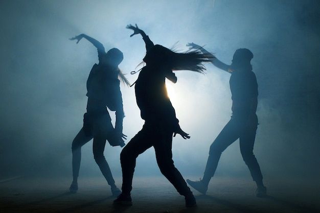 silhouettes of people dancing in the fog with their arms spread out and hands outstretched