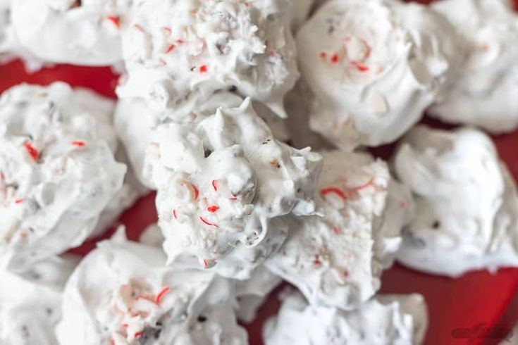 white chocolate and candy canes are piled up on top of each other in a red bowl