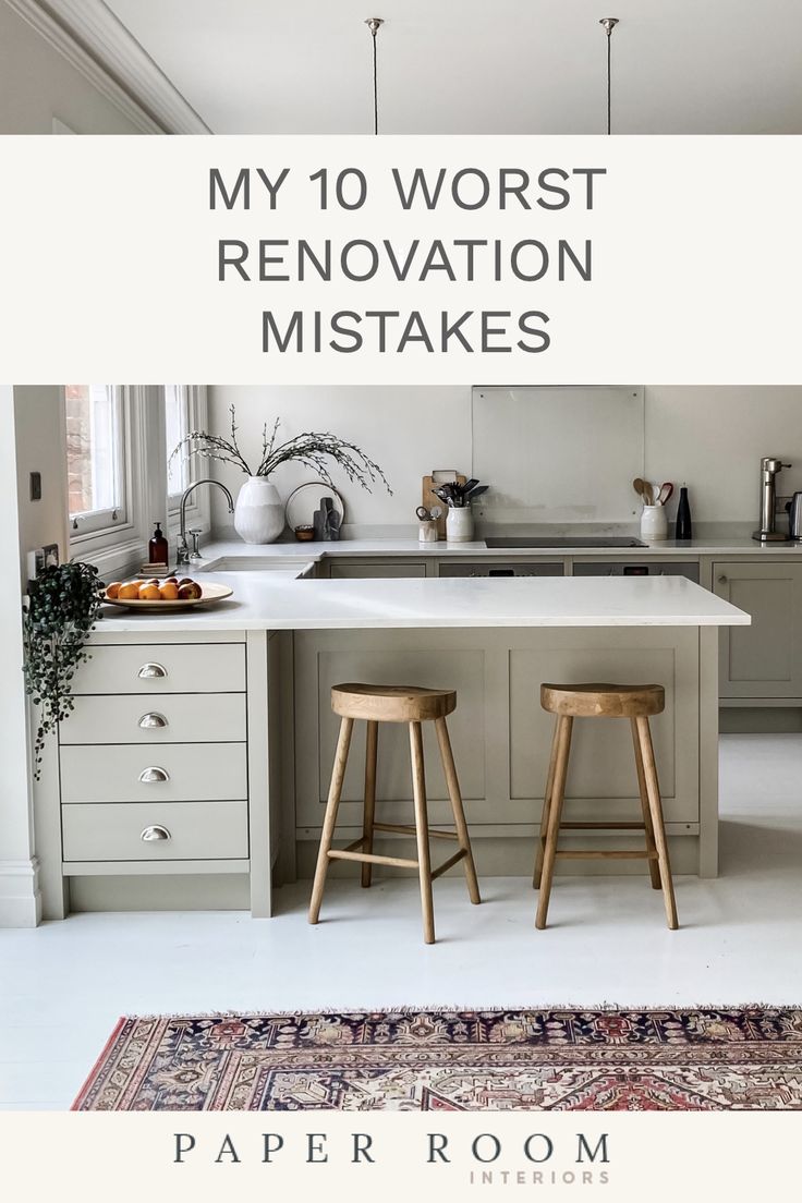 a white kitchen with two stools next to the counter