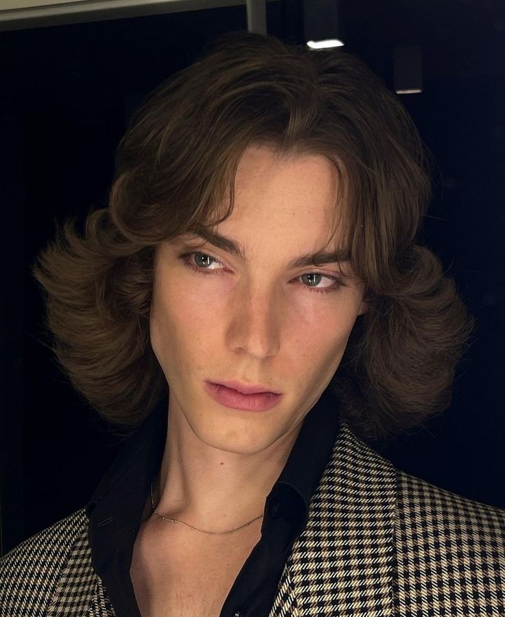 a close up of a person wearing a suit and tie with hair in the wind