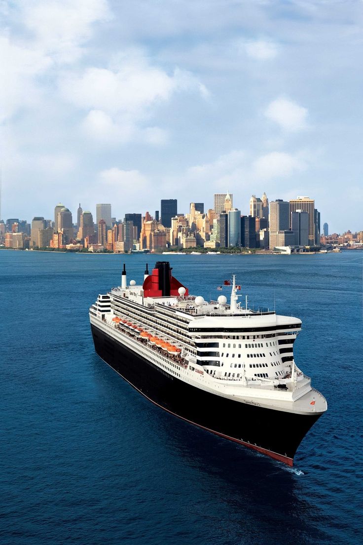 a large cruise ship in the middle of the ocean with a city in the background