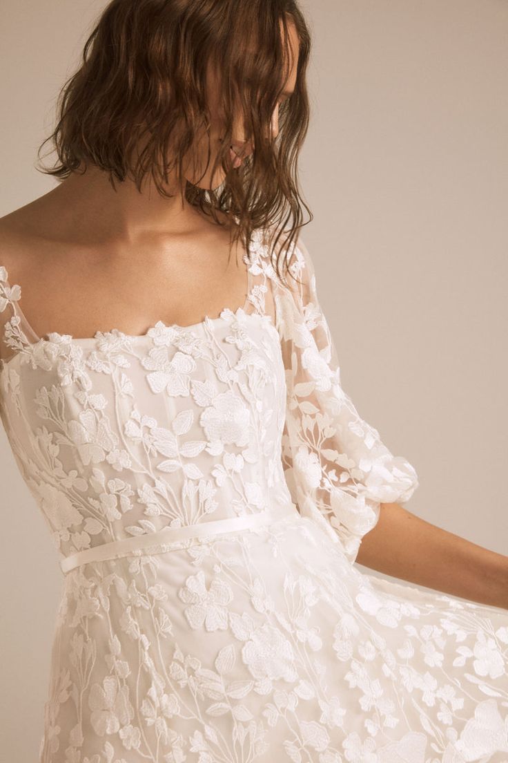 a woman wearing a white dress with flowers on it