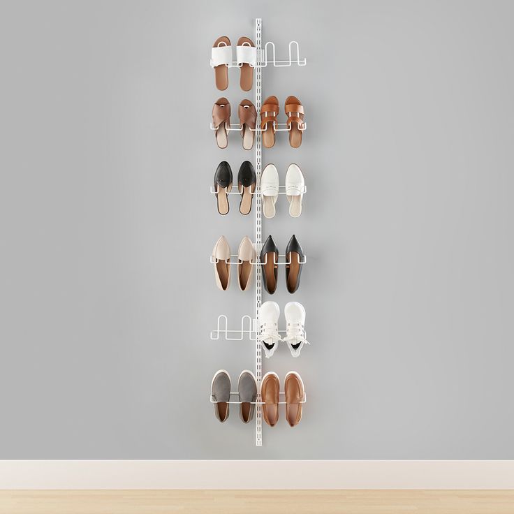 there are many pairs of shoes hanging on the wall in front of a gray wall