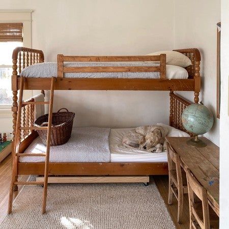 a dog laying on top of a bed in a room next to a wooden table