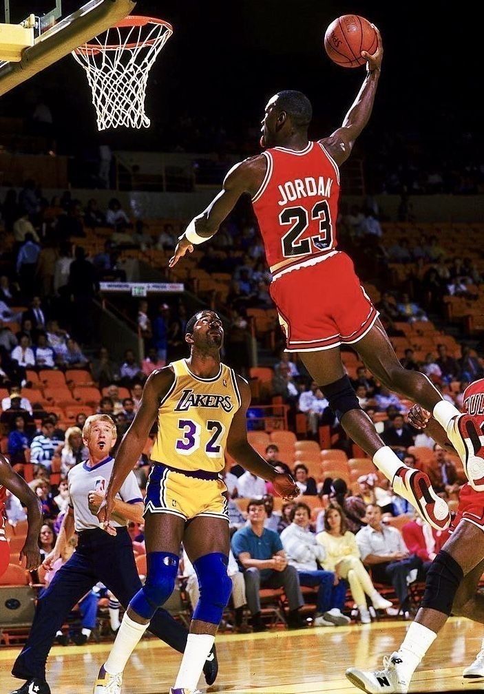 a basketball player jumping up to dunk the ball in front of two other players