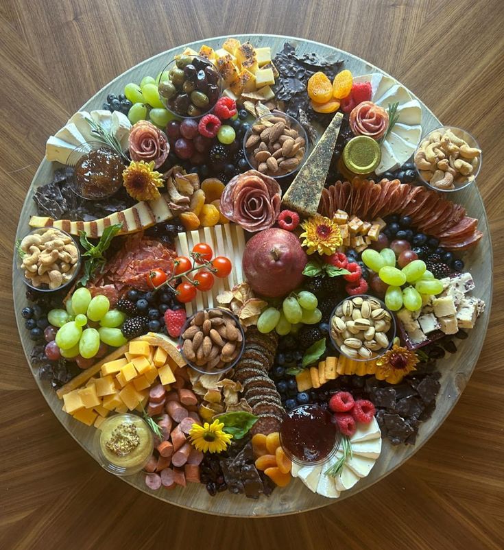 a platter filled with lots of different types of fruits and nuts on top of a wooden table