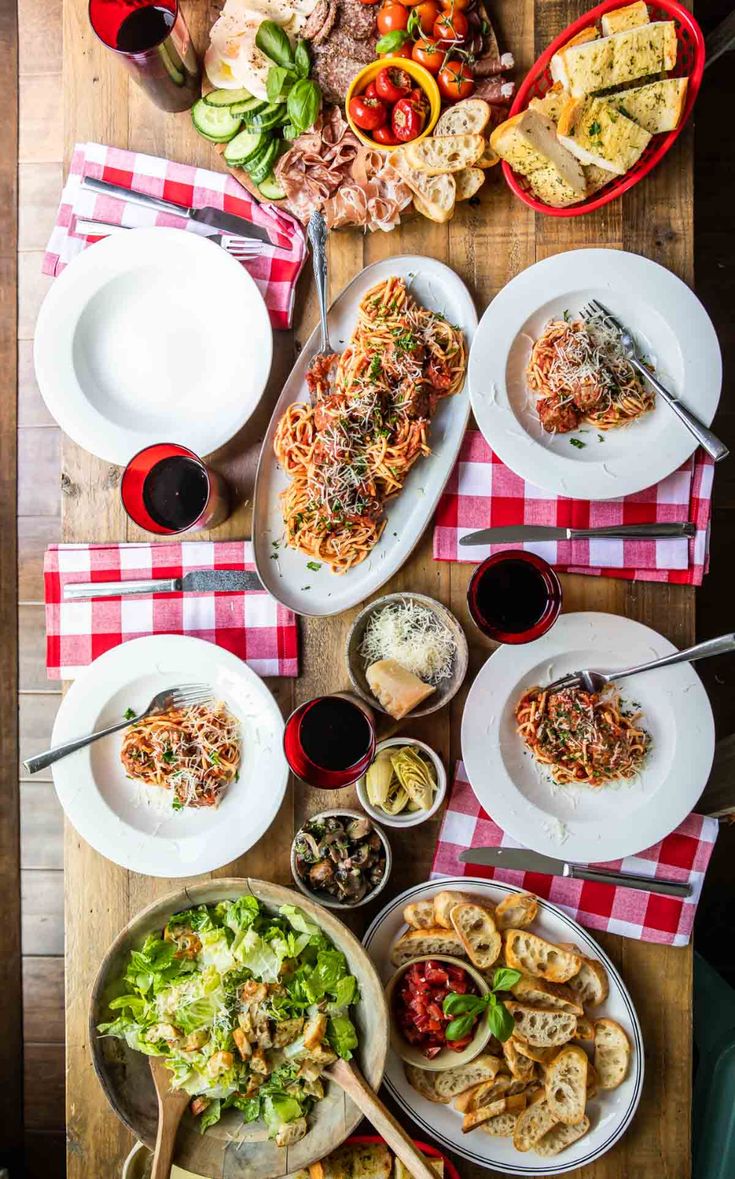 a wooden table topped with lots of plates and bowls filled with different types of food