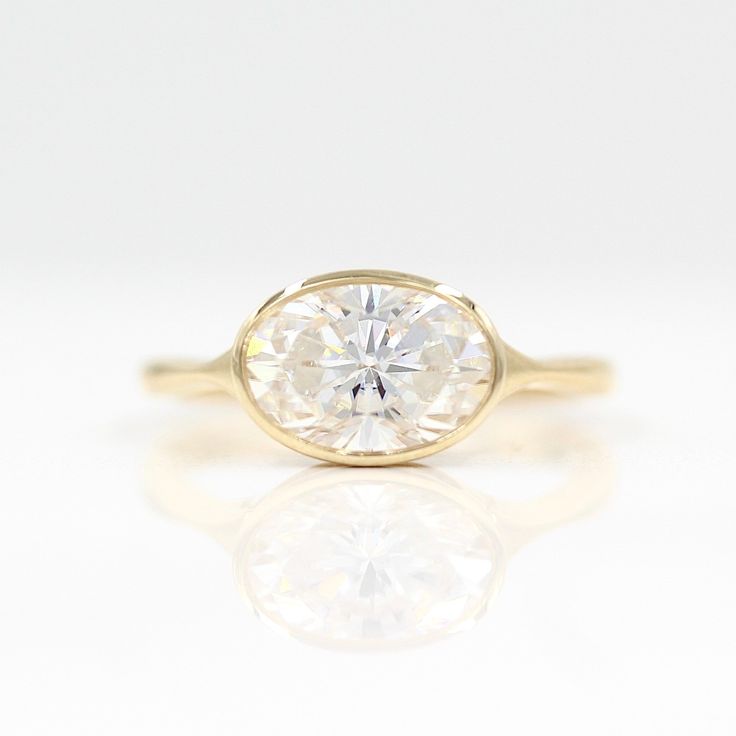 a yellow gold ring with an oval cut diamond