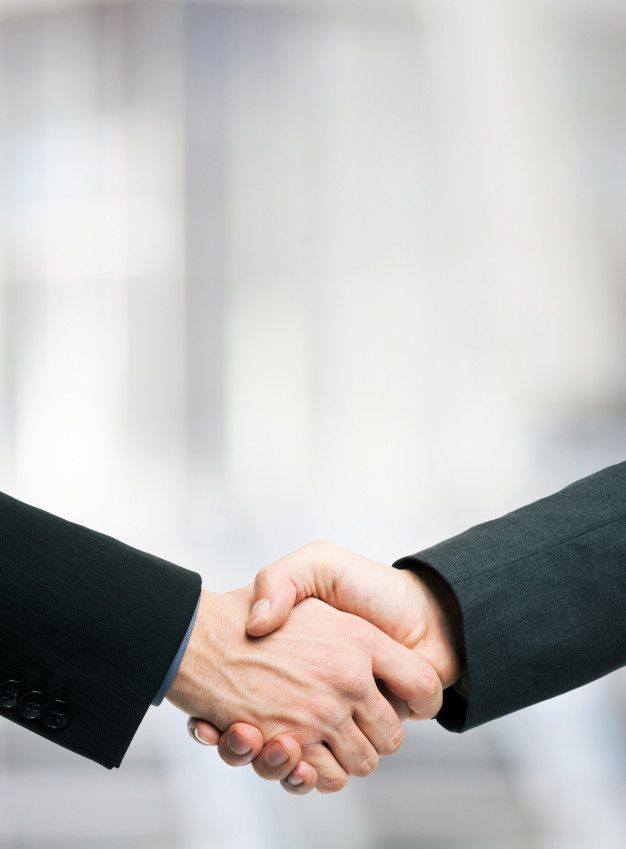 two people shaking hands in front of a building