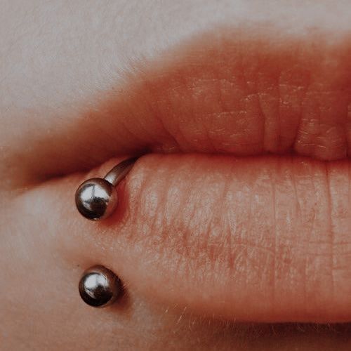 a woman's nose with three balls attached to the side of her lip,