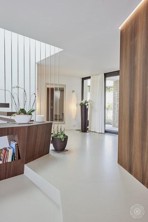 the interior of a modern home with white floors and wood accents on the walls, along with potted plants