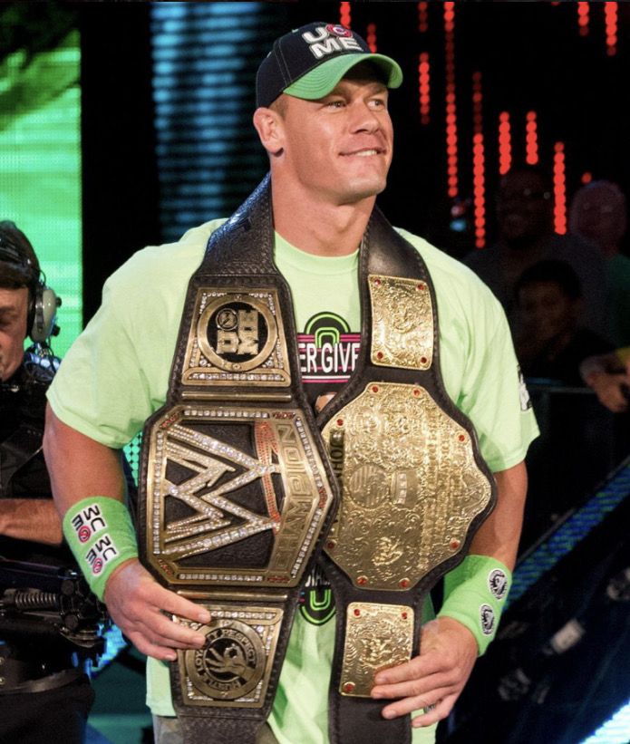 a man standing in front of a camera with a wrestling belt around his neck and wearing a green shirt