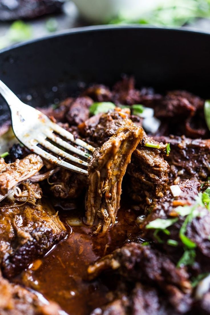 a fork is being used to eat some food in a skillet with meat and sauce