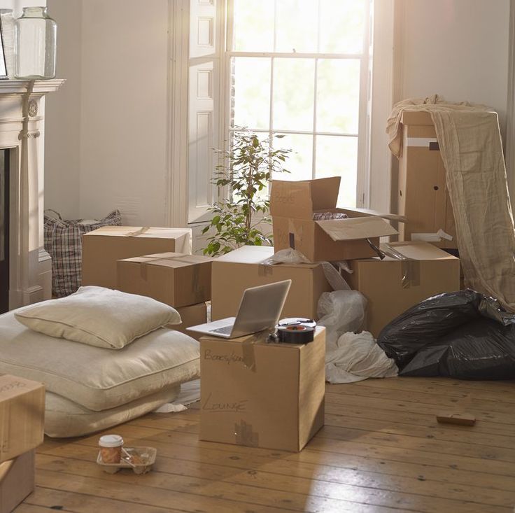 a living room filled with boxes and furniture next to a fire place in front of a window