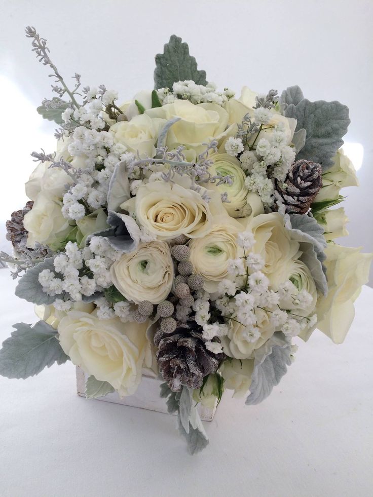 a bridal bouquet with white flowers and pine cones