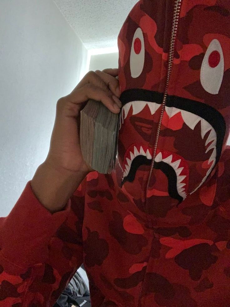 a person in a red camo hoodie holding a cell phone up to their face