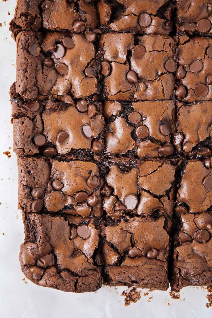 a chocolate brownie cut into squares on top of a white surface with lots of chocolate chips