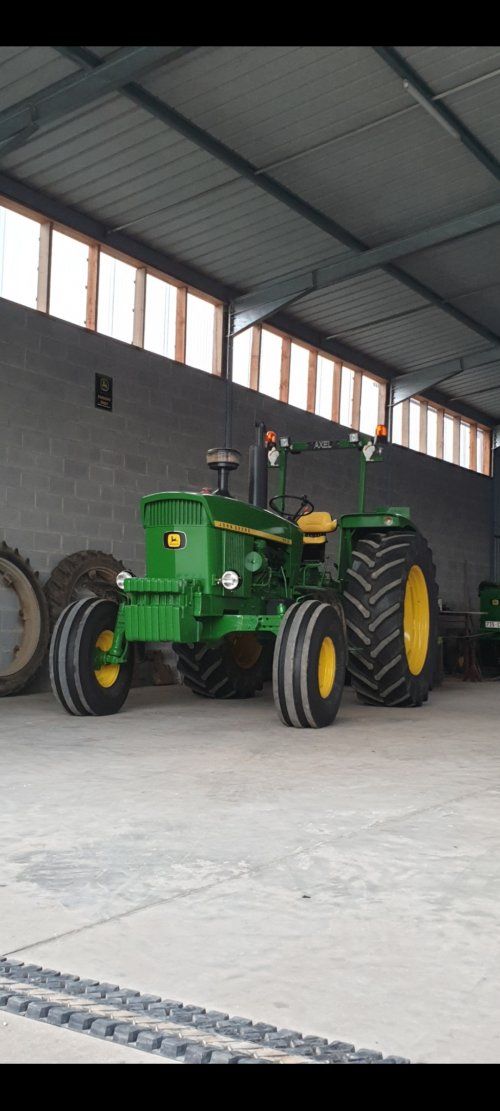 two large tractors are parked in a warehouse with one being pulled by a tractor and the other is attached to a trailer