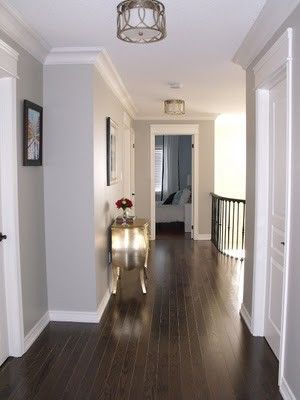 an empty hallway with hard wood flooring and white paint on the walls is shown