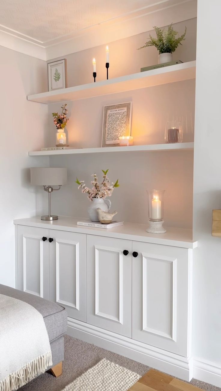 a white shelf with candles and flowers on it