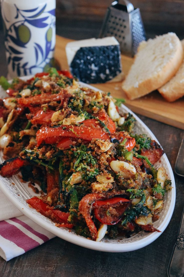 a white plate topped with lots of veggies next to slices of bread on top of a wooden table