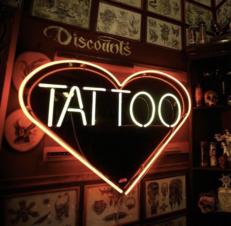 a neon sign that says tattoo in the shape of a heart