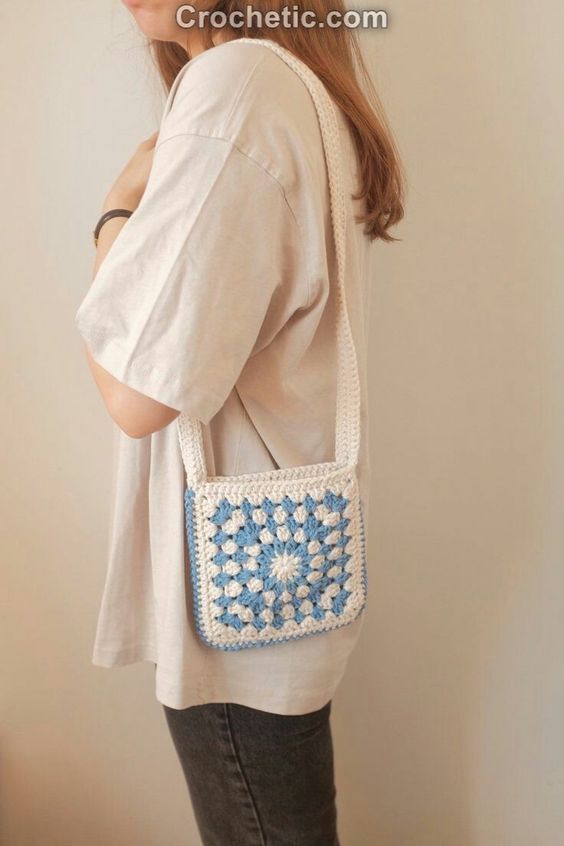 a woman is standing with her back to the camera, holding a white and blue purse