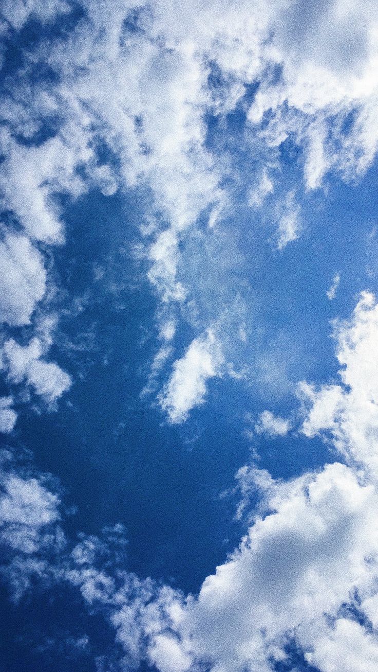 the airplane is flying high in the blue sky with white clouds above it and below