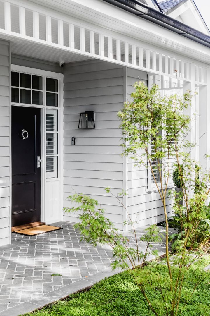 a white house with a black door and some green grass on the side walk way