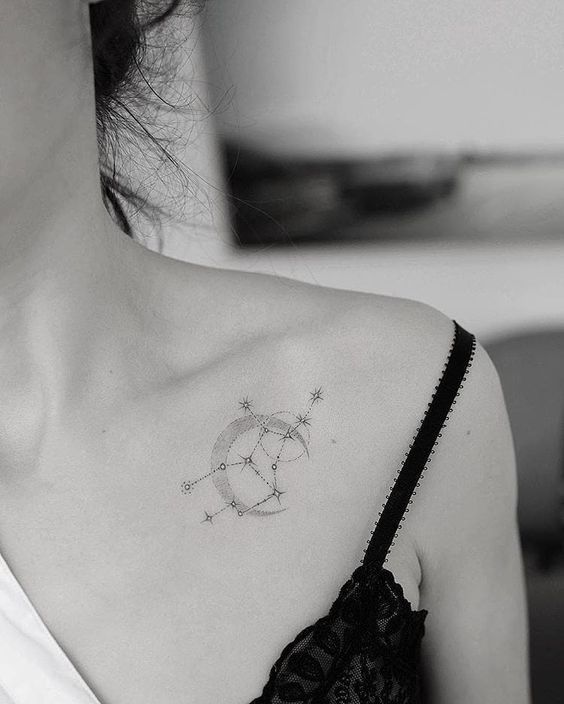 a woman with a star and moon tattoo on her upper back shoulder is looking at the camera