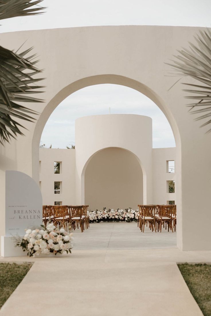 an archway leading into a white building with tables and chairs set up for a formal function