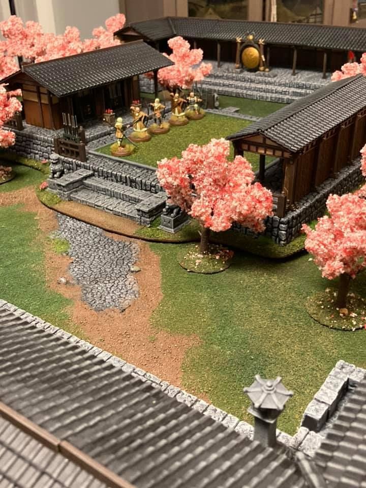 a model of a japanese village with trees and buildings in the foreground, on display