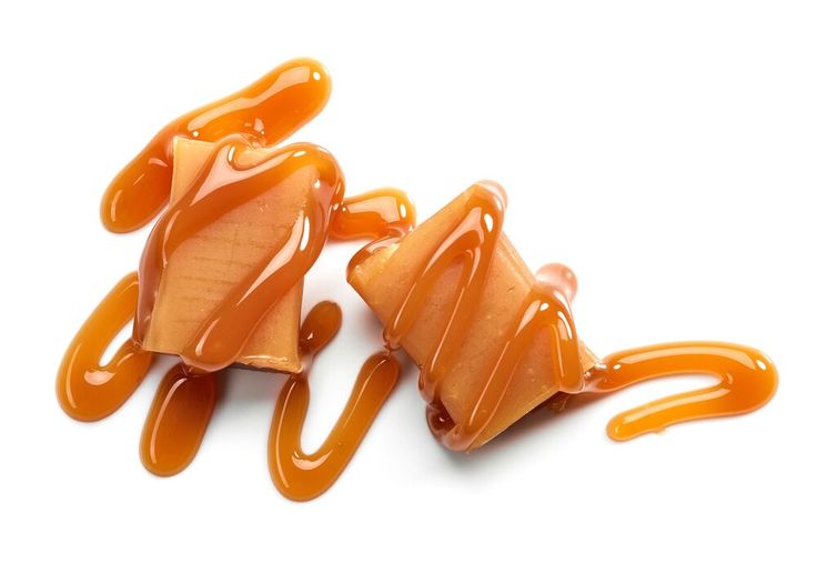 two pieces of caramel on top of each other with sauce drizzled over them