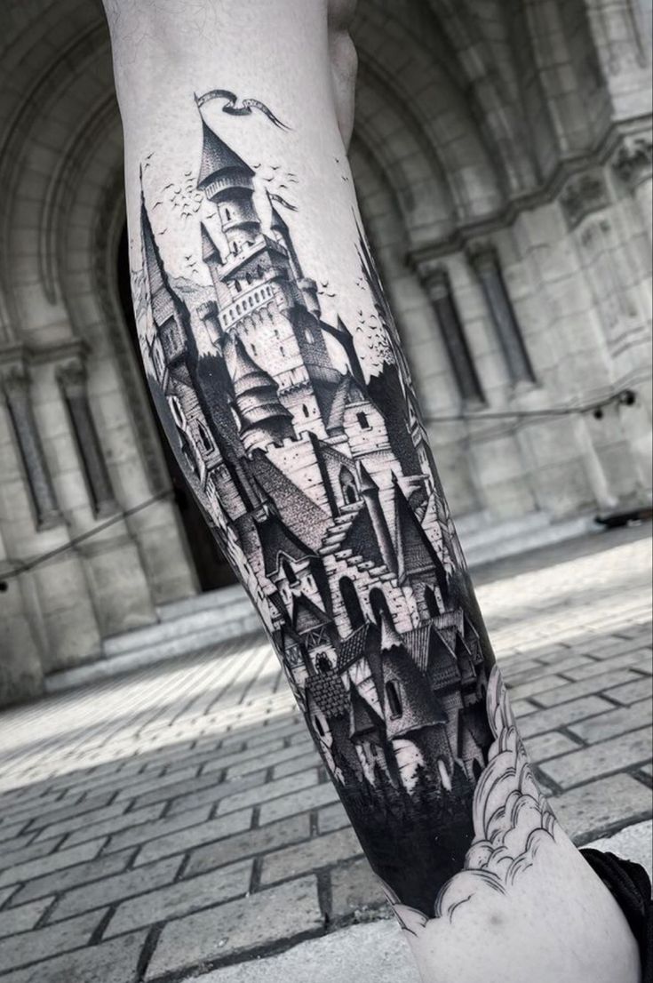 a man's leg with a black and white tattoo on it that has a castle in the middle